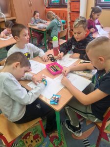 Grupa uczniów kolorująca obrazki