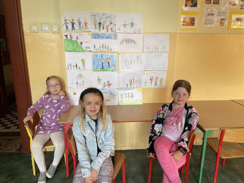Siedzące dziewczynki przed galerią z pracami