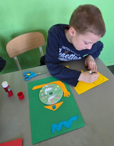 Uczniowie wykonują prace plastyczno techniczną "Zwierzątka" wykorzystując płyty CD